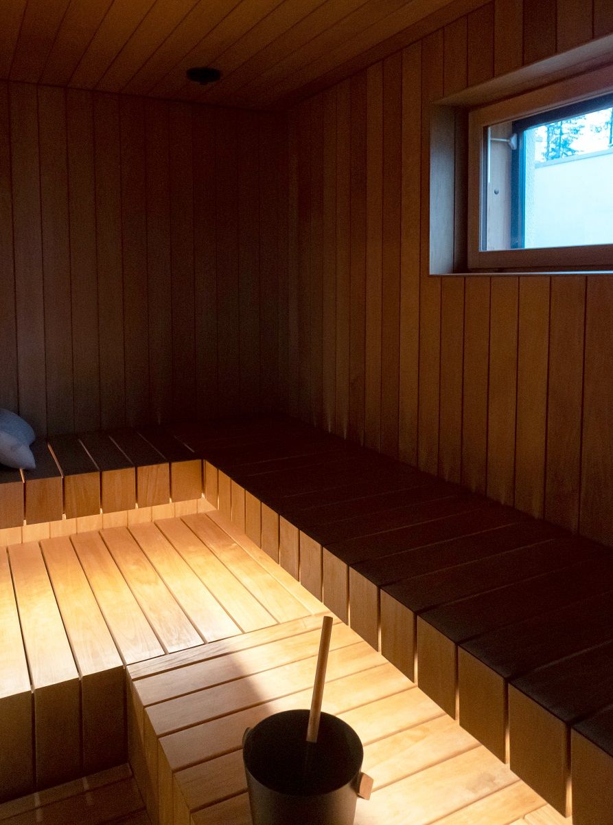 Sul bordo anteriore dell'area di seduta, una striscia LED in una tonalità calda di 3 000 K come luce indiretta illumina le tavole di legno.